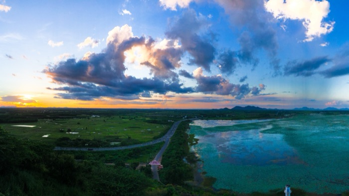 Aerial panorama of green fields and a lake at sunset