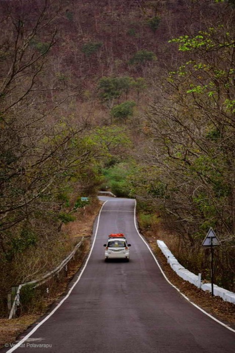 A car on a quiet road winding through forested hills