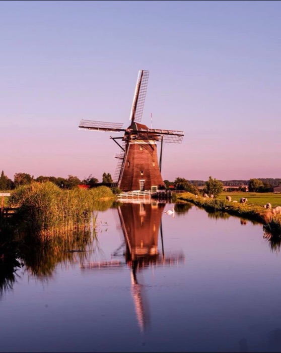 Dutch windmill reflected in water at sunset